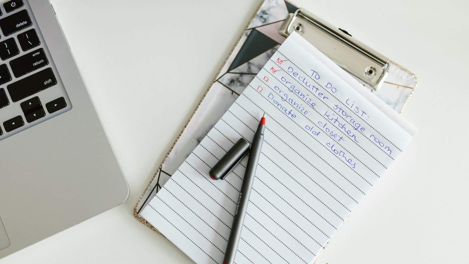 A neatly organized month-end close checklist on a clipboard next to a laptop and pen