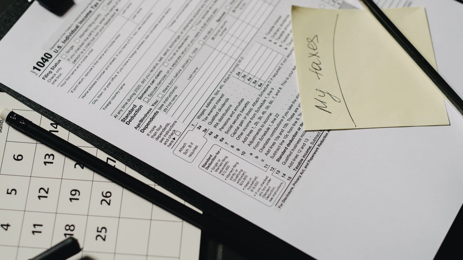 A neatly organized desk with tax forms, a calculator, and stationery used during the month-end close process