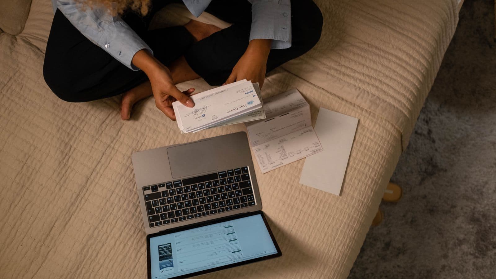 A stack of uncashed paper checks next to a bank reconciliation worksheet, representing outstanding checks
