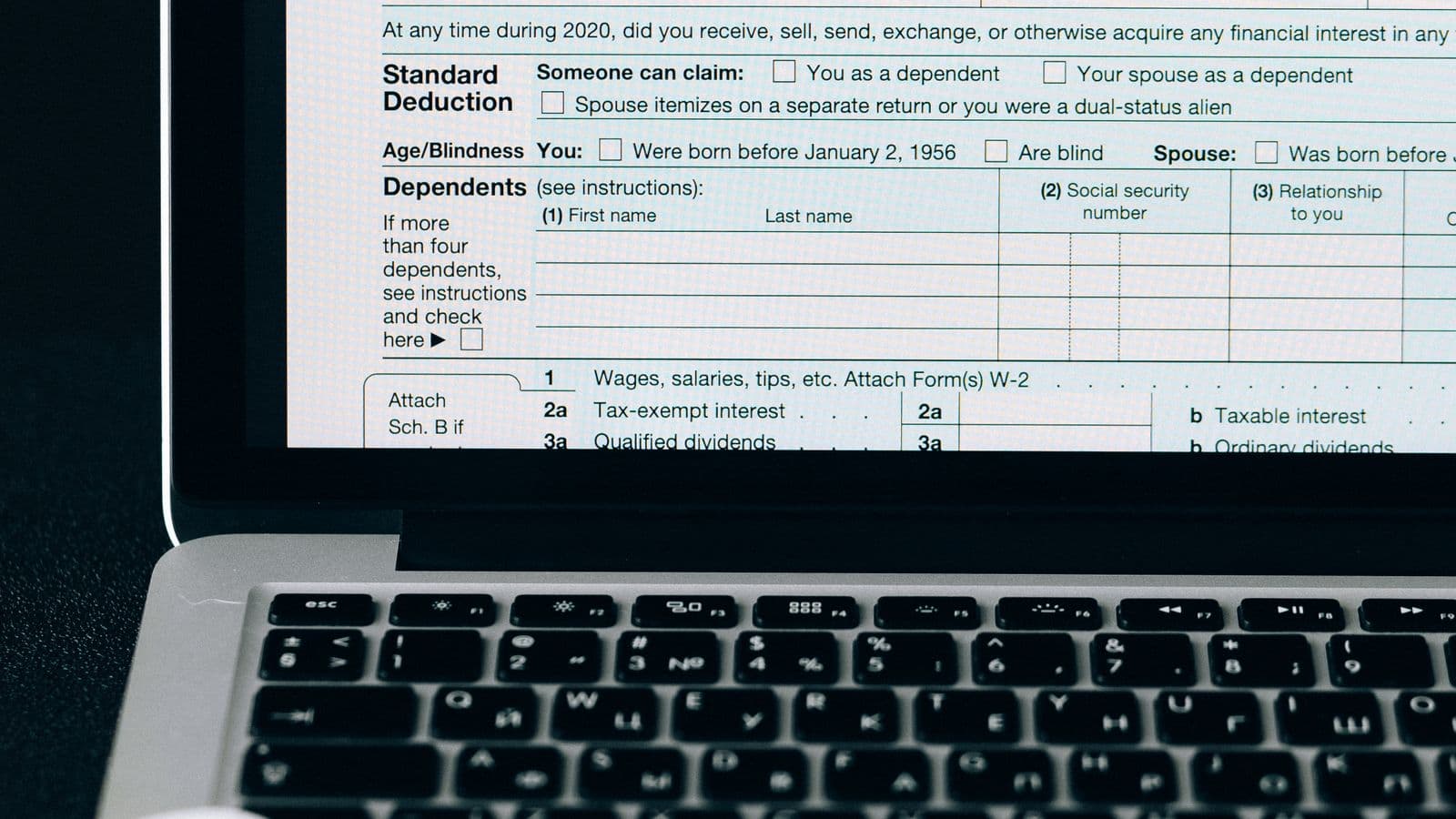 Close-up of a tax form on a laptop screen with a calculator and notebook, representing bank reconciliation software